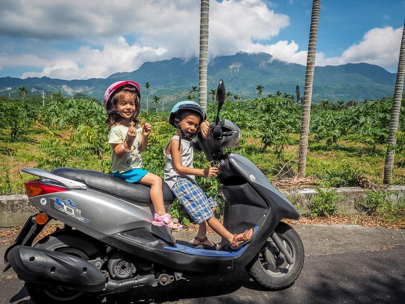 Nick Kembel's two toddler aged kids on a parked scooter in the countryside in Taiwan
