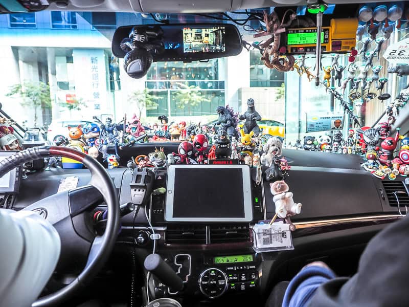 The interior of a taxi with many little toys and decorations on the dashboard