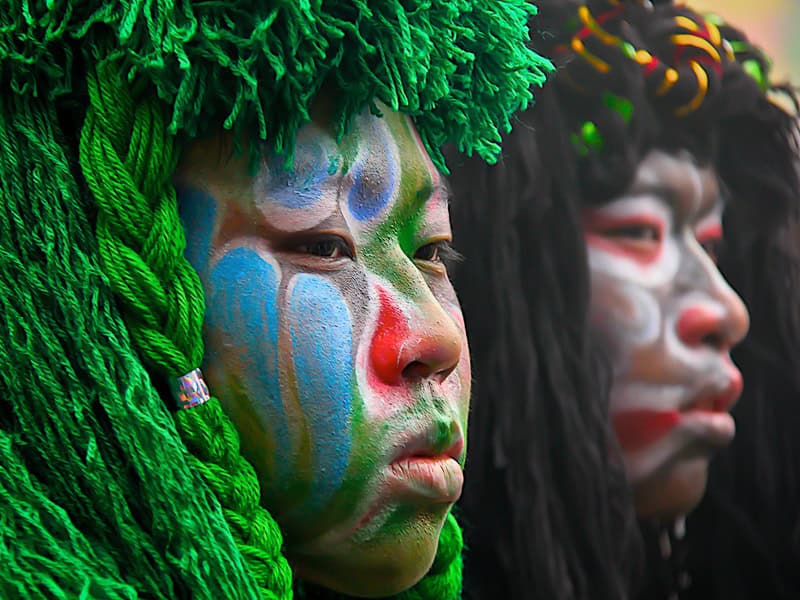 Close up of two Taiwanese boys' faces painted and wearing green and black wigs for a traditional celebration