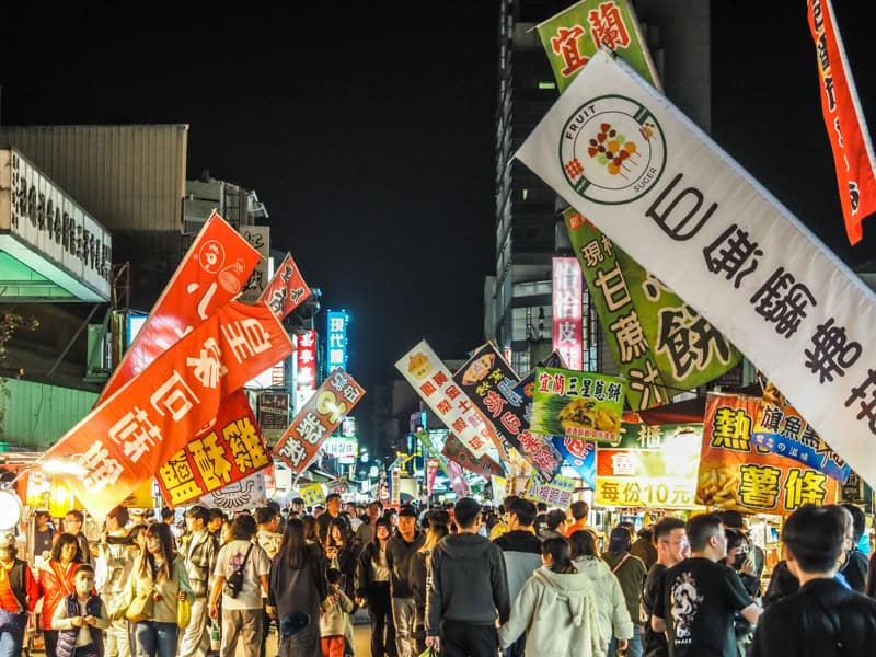 Crowds of pedestrians in Wenhua Road Night Market with many signs above
