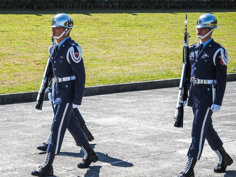 Some guards at CKS Memorial Hall walk down a cement path