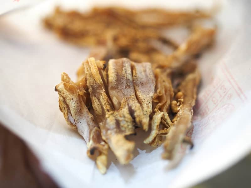 Close-up of some slices of grilled dried squid inside a white paper bag