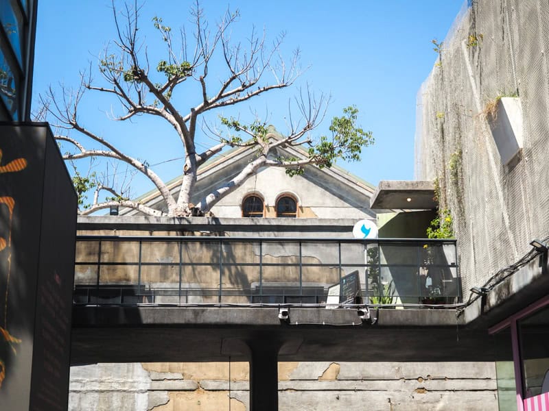 Looking up at an elevated walkway in front of an old factory building at Huashan