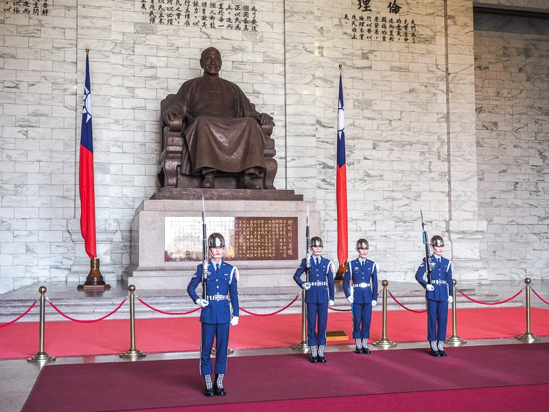 Four uniformed guards standing in front of a seated statue of Chiang Kai Shek