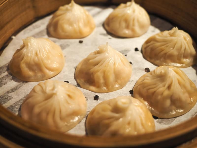 Close up of 8 xiaolongbao in a steaming basket