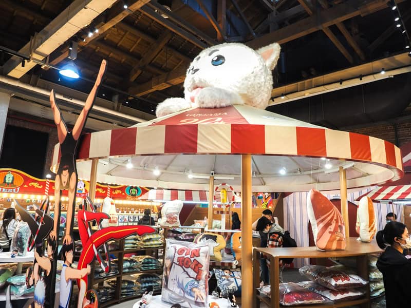 Inside a pop-up store in Huashan Creative Park, with a red and white striped tent with huge cartoon character on top and products for sale under it