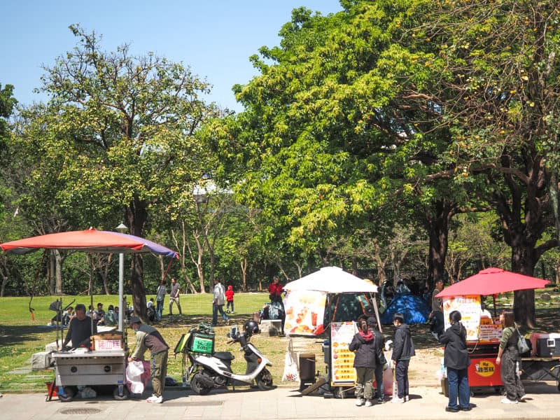 Some food vendors on the side of a grassy park