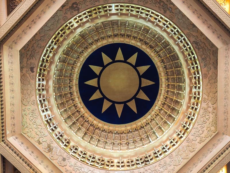 Looking straight up at the white sun on blue background painted inside the dome of CKS Memorial Hall