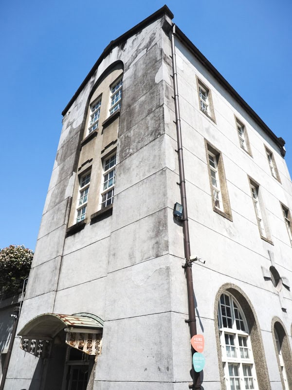 Looking up at a skinny three storey cement building