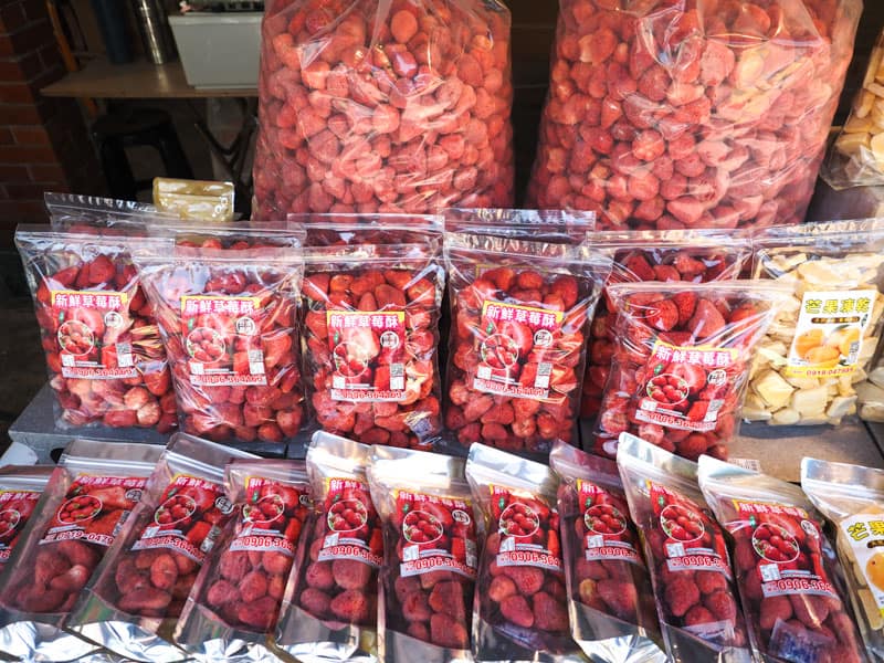 Several bags of dried strawberries on a table, with some especially large bags of them at the back