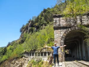 Nick Kembel standing with arms outstretched in front of a train tunnel on Mianyue Line trail in Alishan National Forest Recreation Area