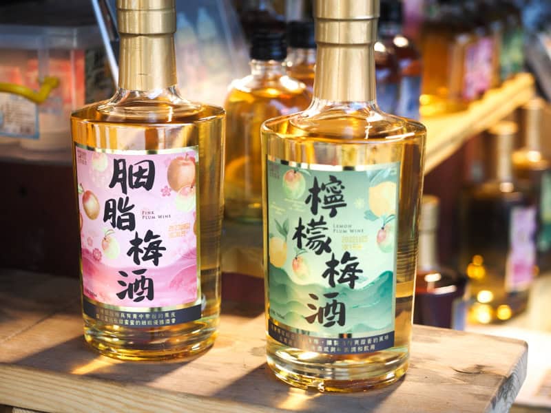 Two bottles of plum wine on a table with their names in Mandarin chracters