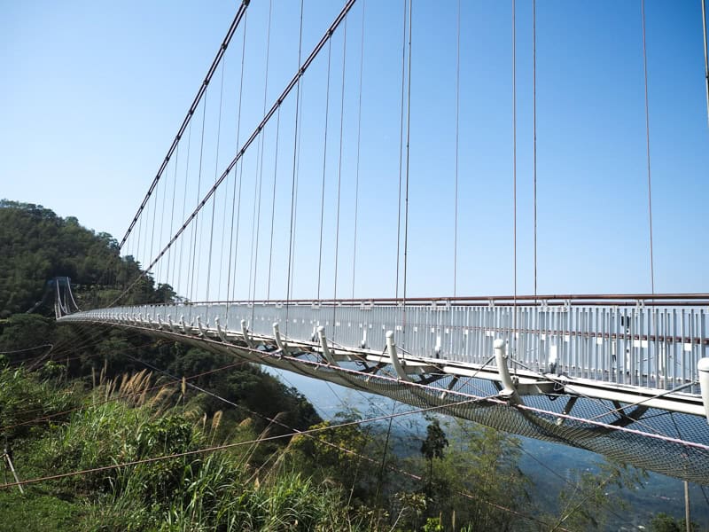 A side view of Taiping Suspension Bridge with valley one side and open blue sky on the other