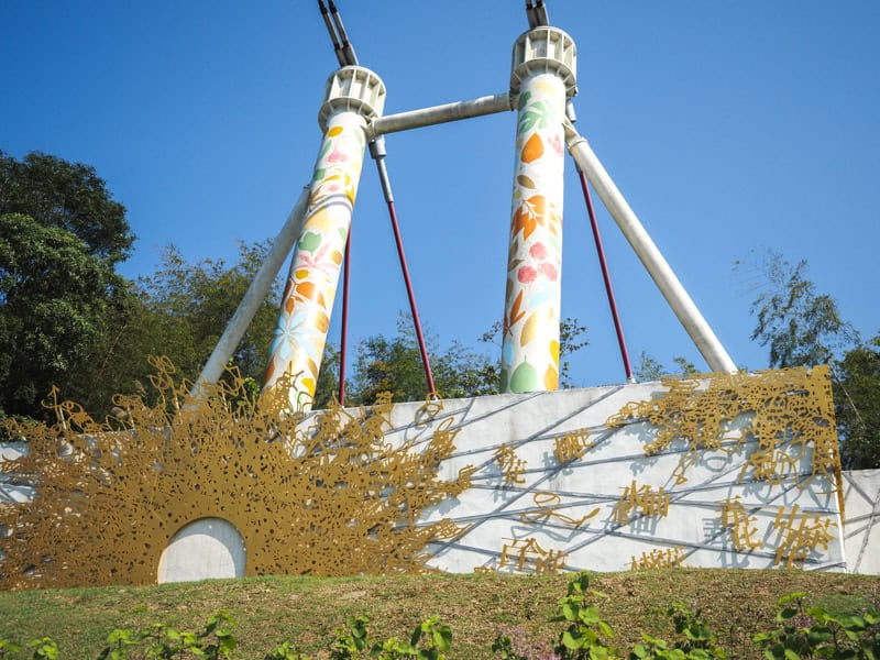 Two tall white columns holding support cables for Taiping Suspension Bridge, with some floral designs on them and more designs on the base