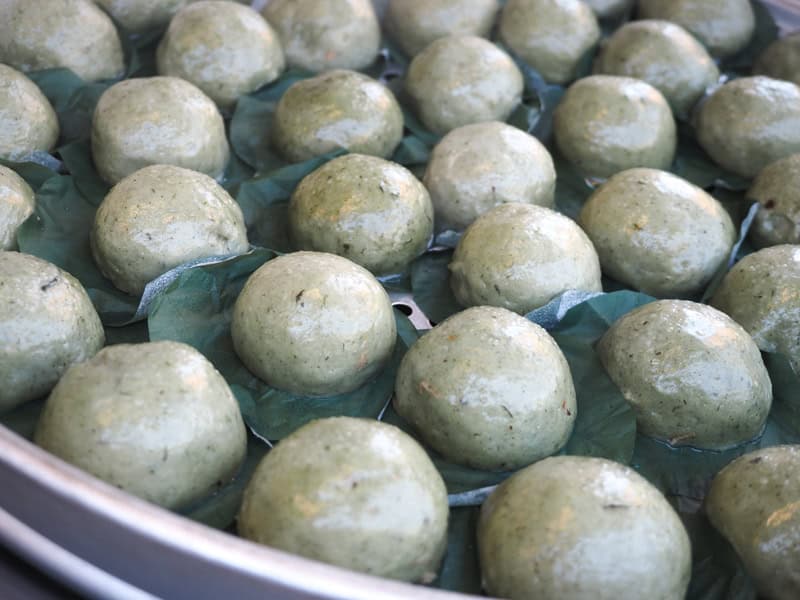Close up of some green sticky rice dumplings on a round metal rack