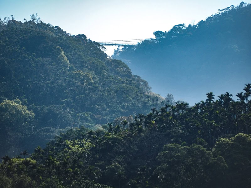 A mountain scene, with Taiping Suspension Bridge visible between two mountains at the top
