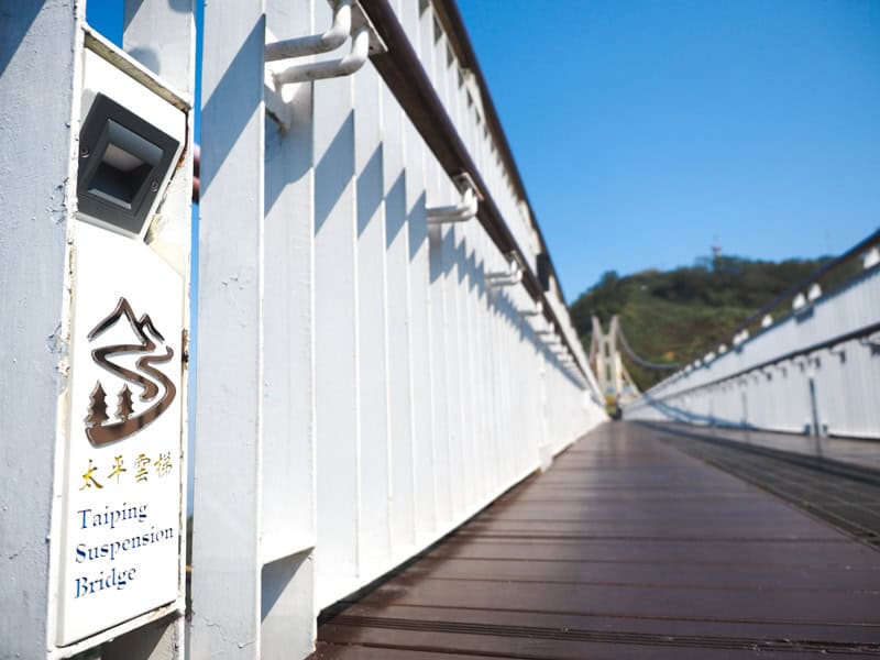 Looking down Taiping Suspension Bridge, shot from close to the deck on one side of it, and the name shown on the white railing on the side