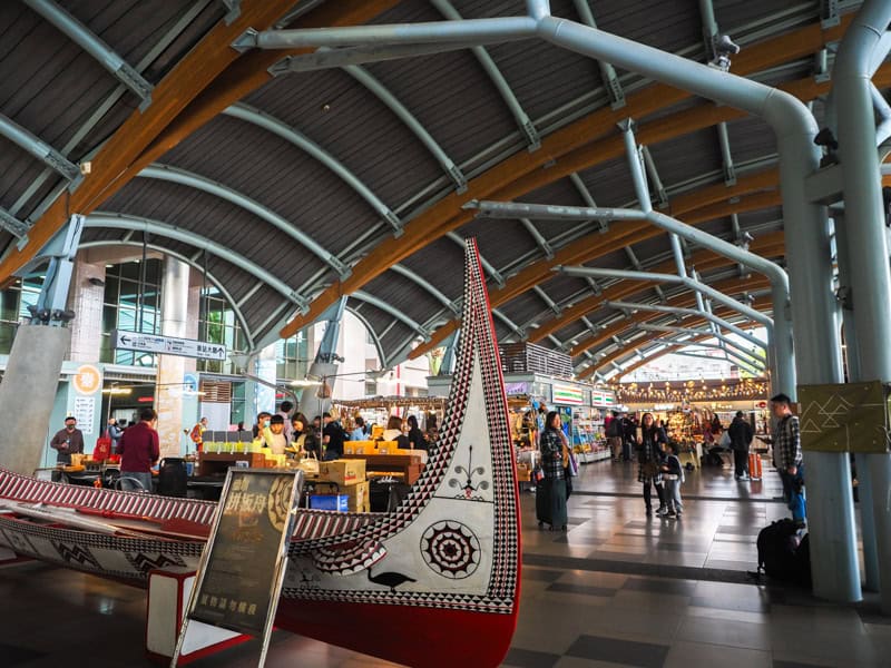 A traditional Tao tribe canoe in Taitung train station with some passengers walking around it