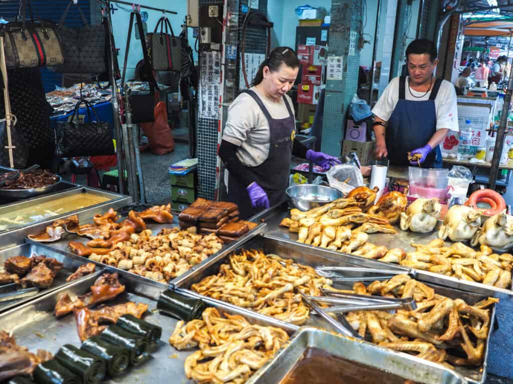 A vendor couple with large display of cooked food items in front of them