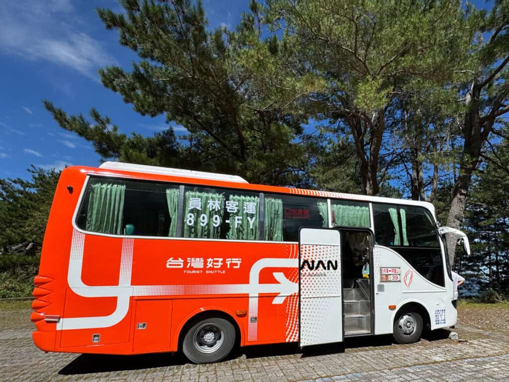 A red and white Taiwan shuttle bus on a break in a parking lot on the drive from Sun Moon Lake to Alishan