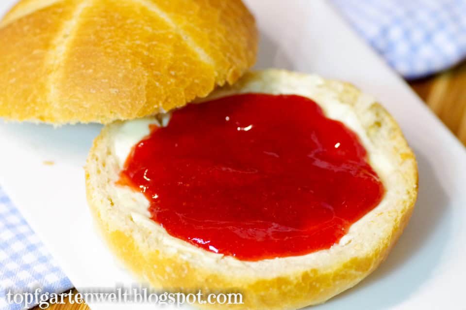 Eine Semmel mit Butter bestrichen mit selbst gemachter Erdbeerkonfitüre - Foodblog Topfgartenwelt