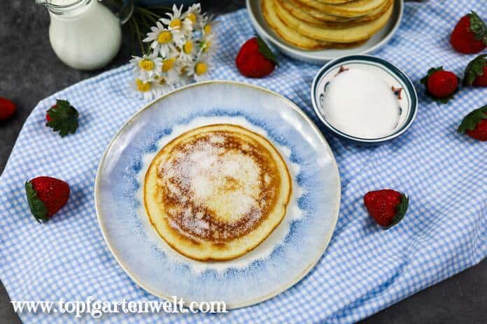 Pfannkuchen mit Eischnee auf einem blauen Teller. Im Hintergrund steht eine kleine Kanne Milch.