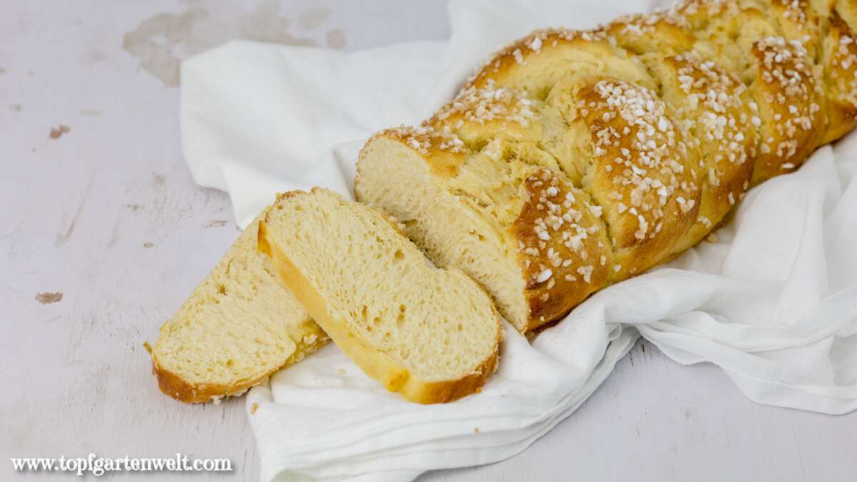 Auf einem weißen Tuch liegt ein angeschnittener Allerheiligenstriezel.