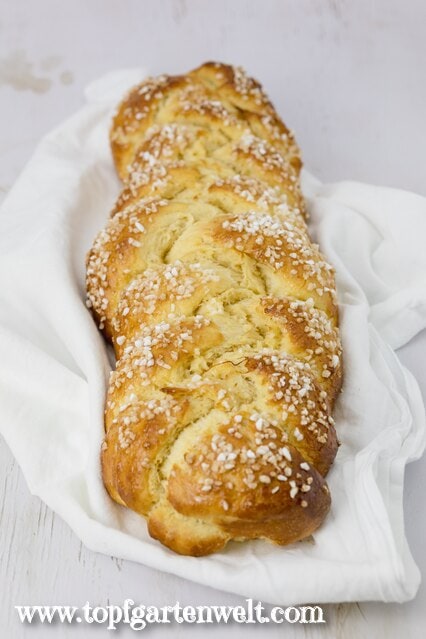 Dieser Allerheiligenstriezel, welcher auf einem weißen Tuch am Frühstückstisch platziert ist, wartet darauf angeschnitten zu werden.