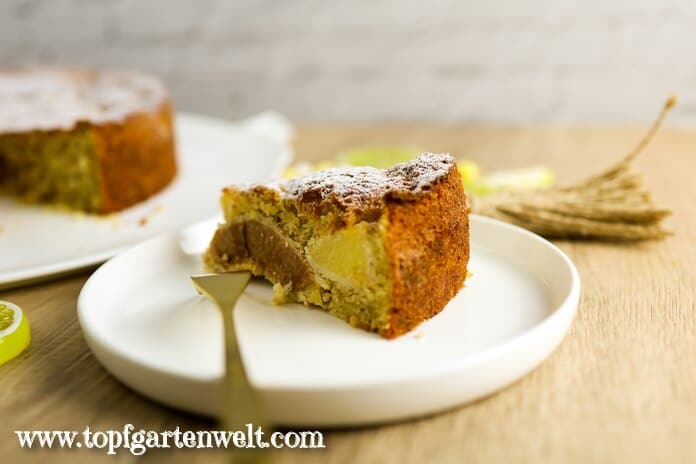 Ein Stück saftiger Quittenkuchen aus Rührteig ist auf auf einem weißen Teller angerichtet. Eine goldene Gabel liegt schon bereit.