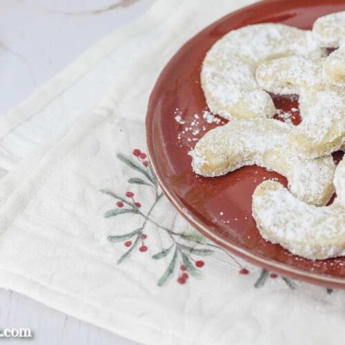 Vanillekipferl ohne Mandeln auf einem weißen Teller. Im Hintergrund ein weihnachtliches Tuch. Foodblog Topfgartenwelt