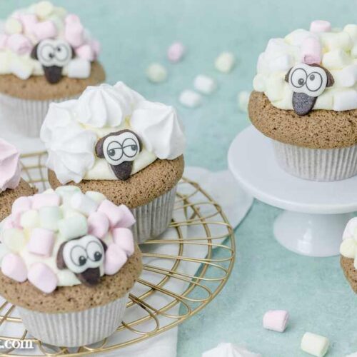Schäfchen Muffins stehen auch einem goldenen Abkühlgitter. Sie sind mit Baiser-Tupfen und Mini-Marshmallows verziert.