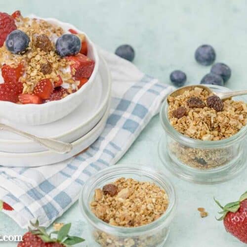 Selbst gemachtes Knuspermüsli in einem kleinen Weck-Glas. Daneben steht eine Schüssel mit Obstsalat.