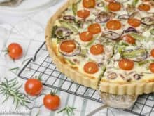 Diese Quiche mit grünem Spargel und Tomaten schmeckt vorzüglich. Verfeinert ist sie mit Speck, Rosmarin und Zwiebelringen.
