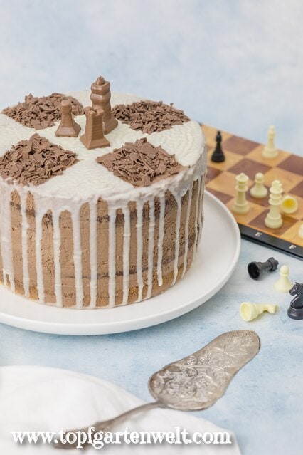 Diese Schachbretttorte ist mit einem Turm, König und Bauern aus Schokolade verziert. Das sieht sehr ansprechend aus.