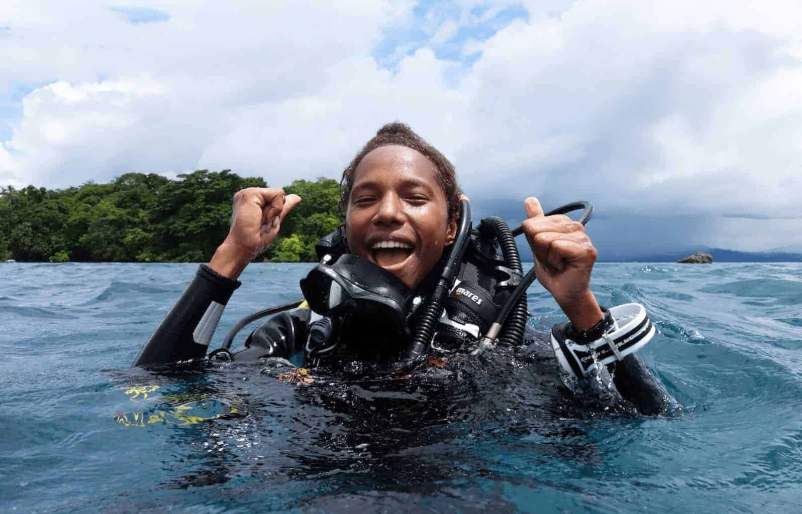 One of the conservationists naomi longa
a man in scuba gear coming up in the water smiling and cheering