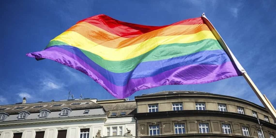 Trans rights are under attack. A rainbow flag in a city blows in the wind