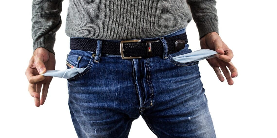 A man with empty jean pockets pulled inside out