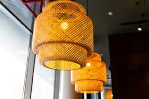 Three woven rattan pendant lights hang from the ceiling, illuminated and casting a warm, soft glow.