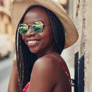 A smiling woman with long braids wearing a sun hat and reflective sunglasses, posing during a professional corporate group session in warsaw.
