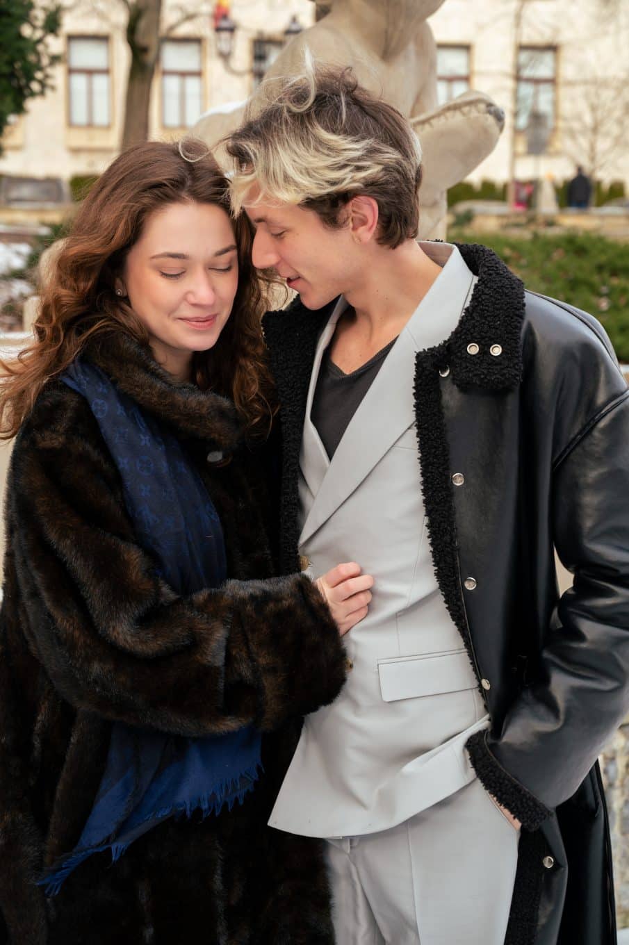Para w modnych, ciepłych ubraniach (futro i elegancki płaszcz) pozująca w plenerze miejskim. Sesja zdjęciowa warszawa dla par