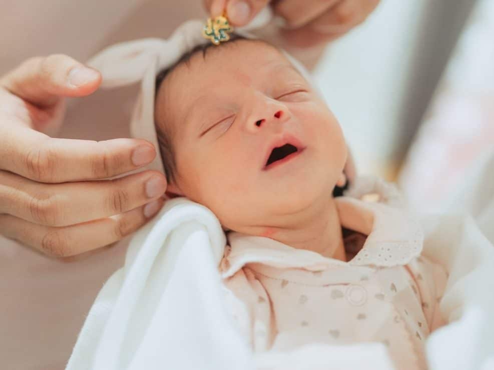 Bliski kadr: chrzest zdjecia noworodka w dłoniach rodziców. Intymny reportaż chrzest wykonany przez fotograf chrzest warszawa