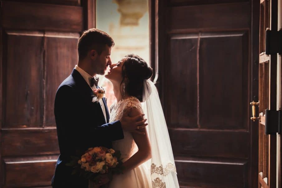 Intymna chwila pary młodej w drzwiach – profesjonalna fotografia ślubna i reprtaż ślubny z warszawy.
