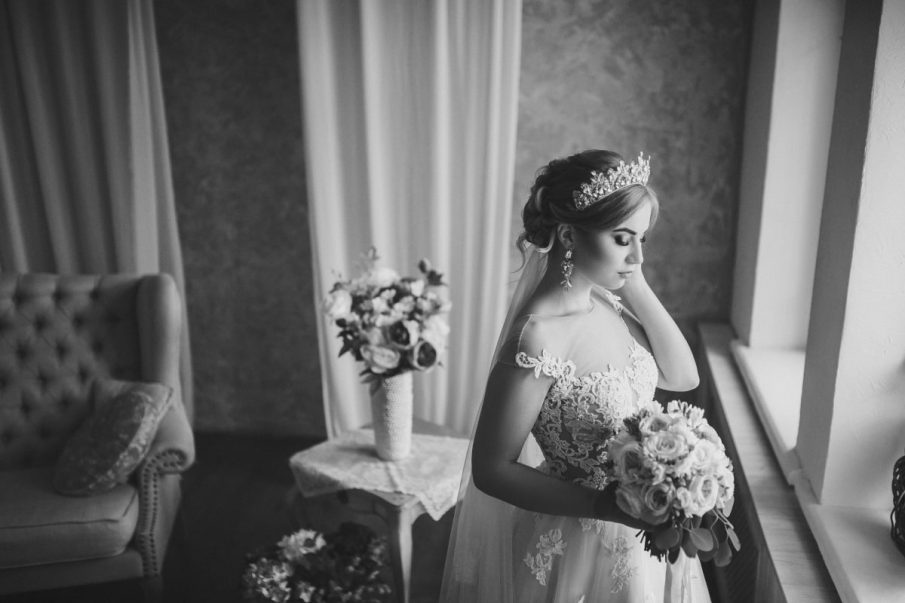 Klasyczna fotografia slubna panny młodej z bukietem i tiarą. Nastrojowy reprtaż ślubny w czerni i bieli