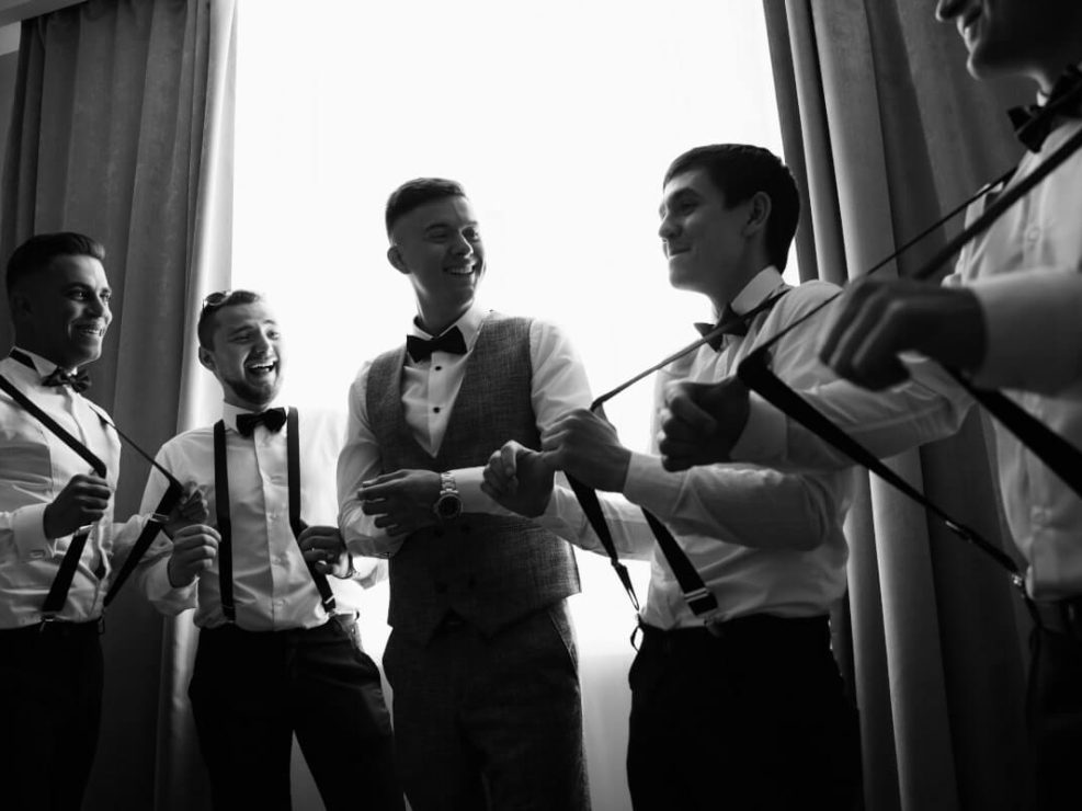 Fotografia weselna: przygotowania pana młodego i drużbów w szelkach. Dynamiczny reportaż ślubny w warszawie.
