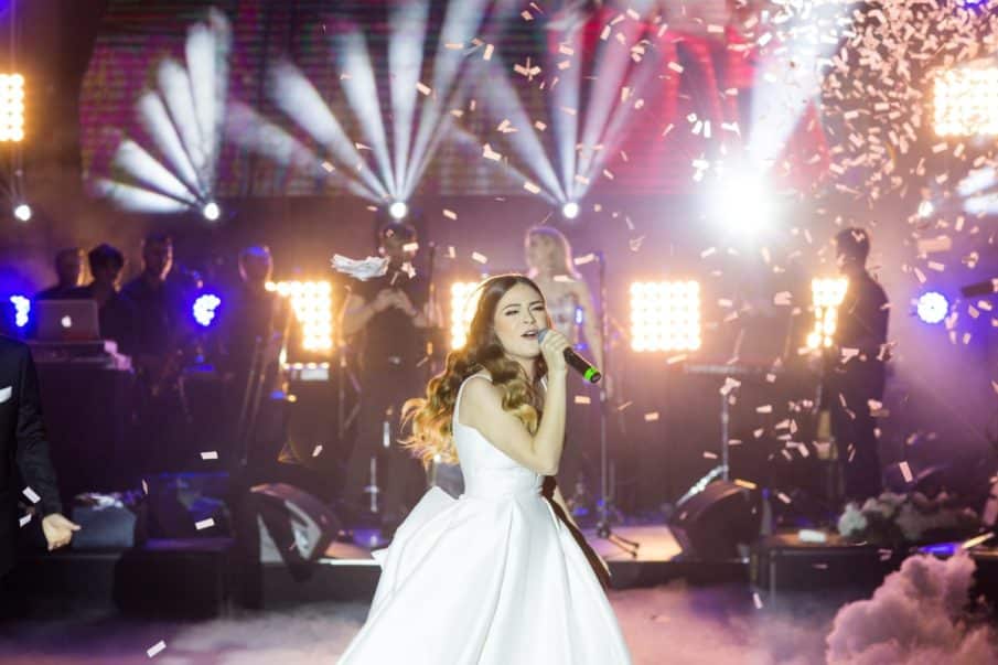 Fotografia weselna: dynamiczny reportaż ślubny uwieczniający występ wokalny na scenie w blasku świateł