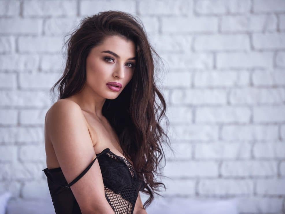 Zmysłowy portret sesja sensualna: Brunetka z opuszczonym ramiączkiem w czarnej bieliźnie. Kadr podkreślający dekolt i intymność sesji boudoir w apartamencie.