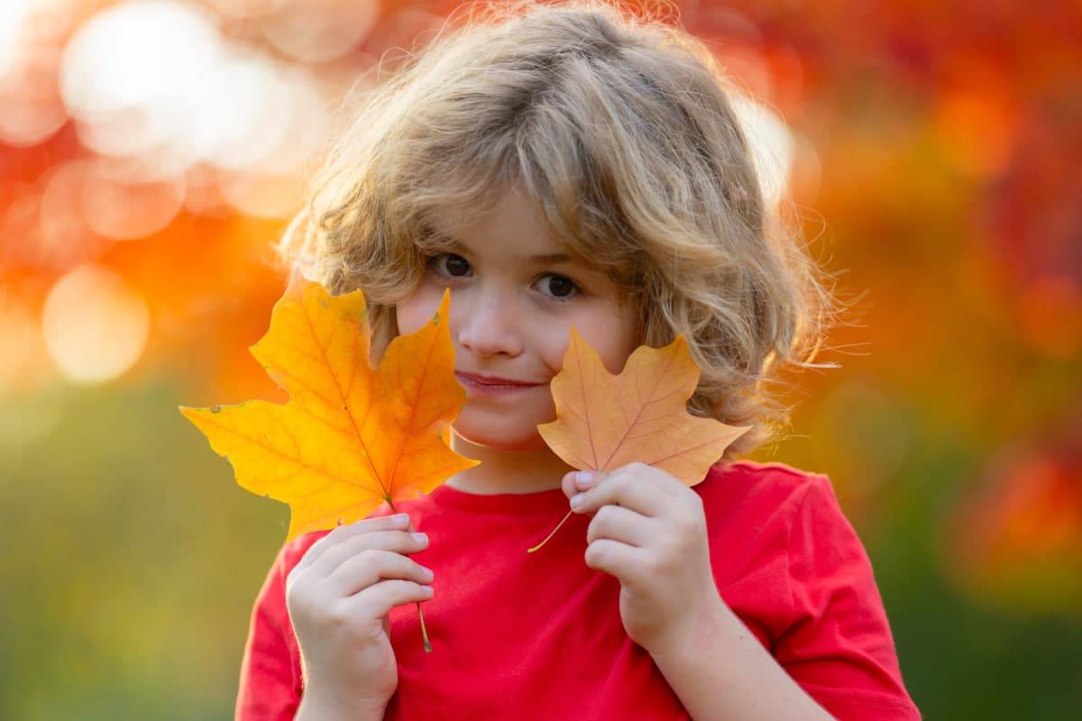 Rodzinna sesja zdjęciowa w łazienkach królewskich w warszawie. Dziecko bawi się jesiennymi liśćmi.