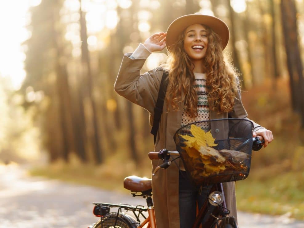 Sesja jesienna kobieca z kobietą jadącą na rowerze w złotym parku. Zdjęcia jesienne lifestylowe w warszawie.