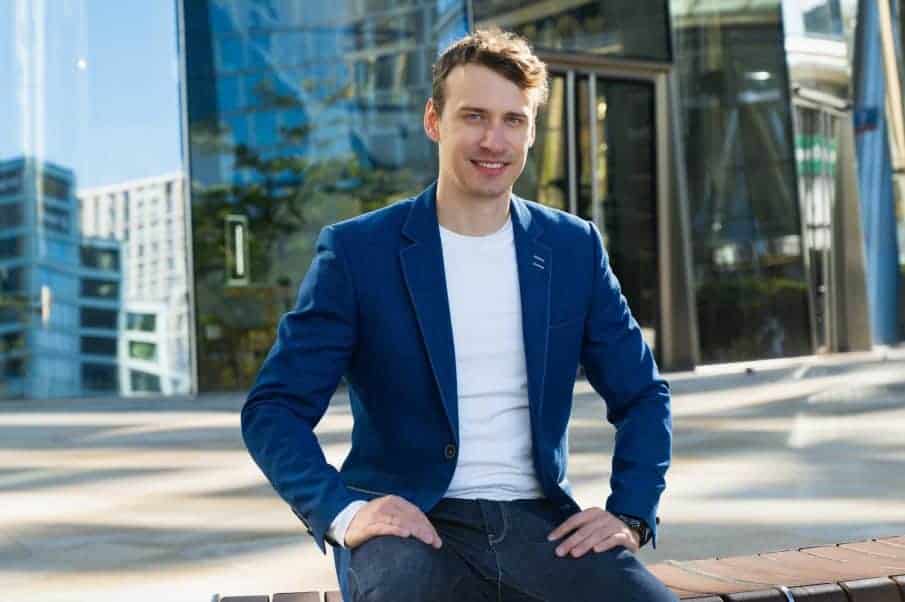 Fotograf warszawa w marynarce i białej koszulce na tle szklanego wieżowca