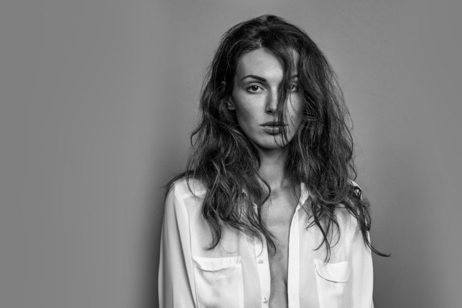 Fotografia kobieca. Emocjonalny portret czarno-biały kobiety w rozpiętej koszuli, z burzą włosów. Sesja zdjęciowa kobieca.